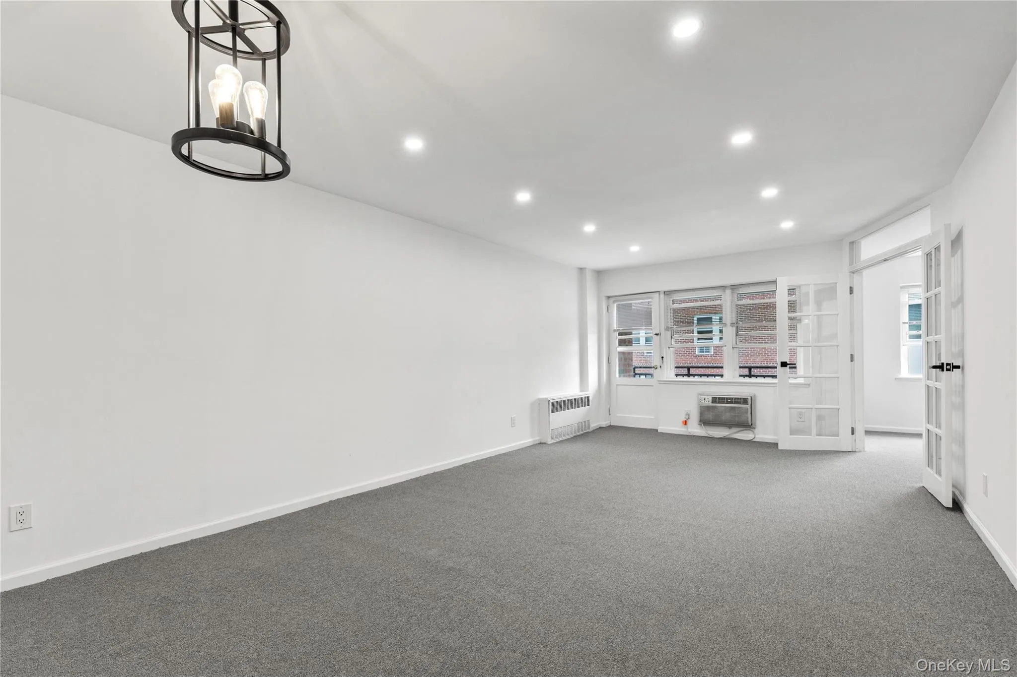 Unfurnished living room with recessed lighting, carpet, and radiator Unfurnished living room with recessed lighting, carpet, and radiator