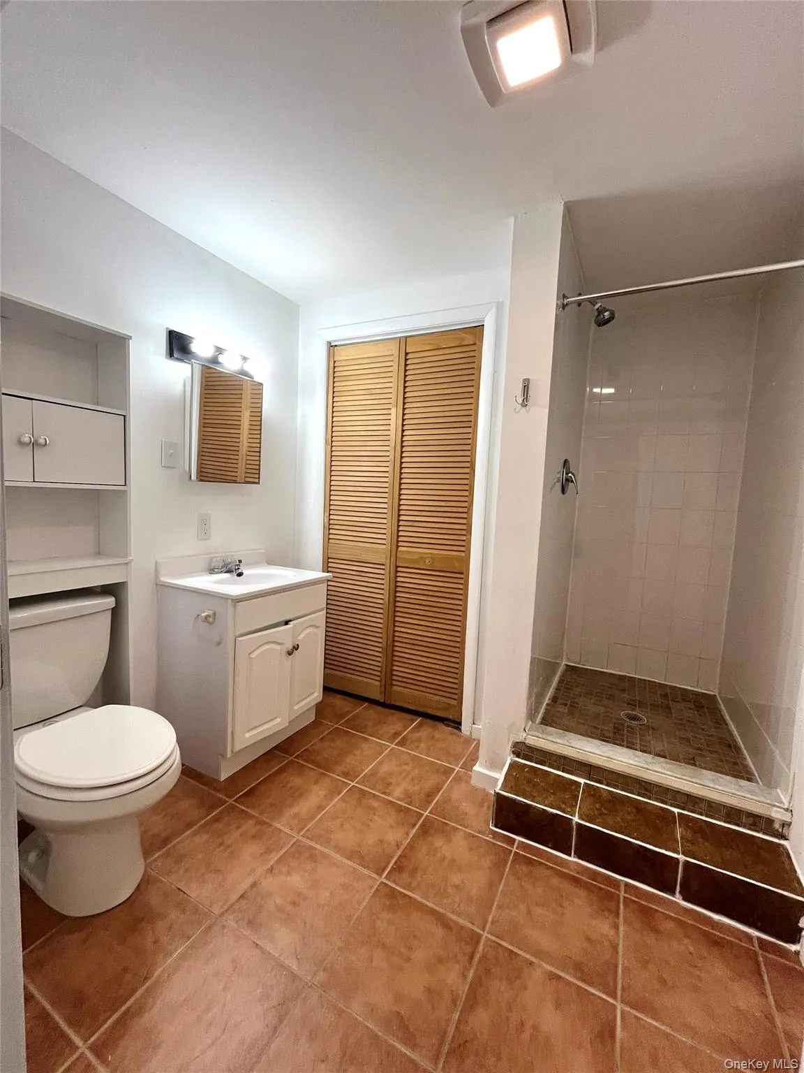 Bathroom with light tile patterned floors, vanity, a shower stall, and a closet Bathroom with light tile patterned floors, vanity, a shower stall, and a closet