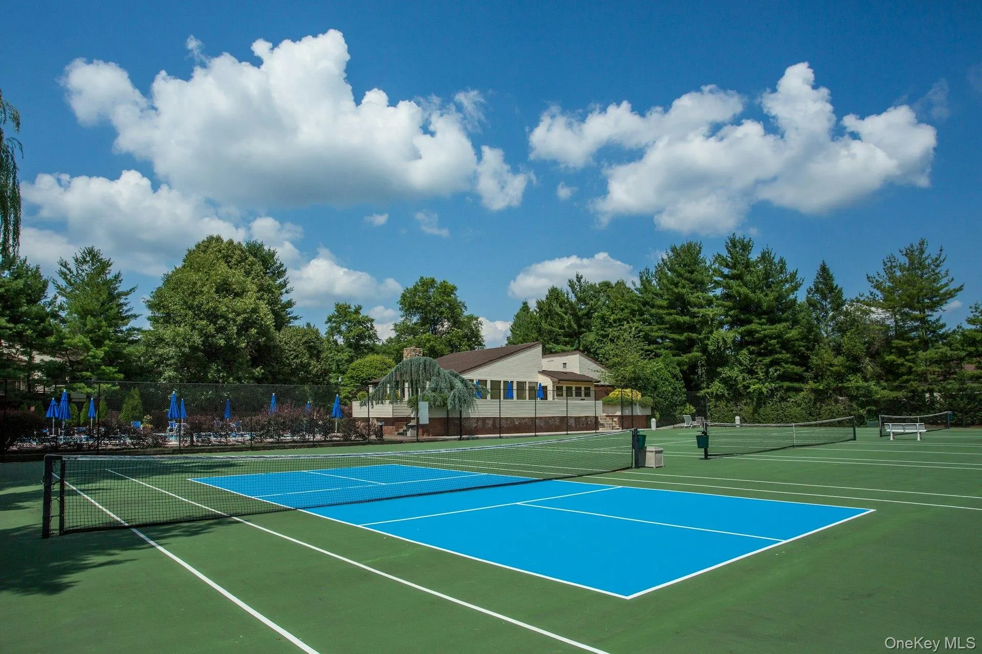 View of tennis court with community basketball court and view of wooded area View of tennis court with community basketball court and view of wooded area
