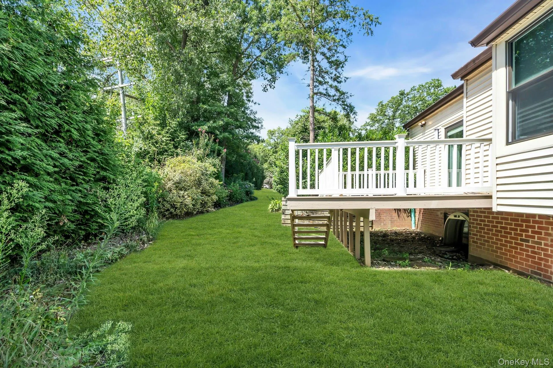 Back View of grassy yard featuring a deck and view of scattered trees Back View of grassy yard featuring a deck and view of scattered trees