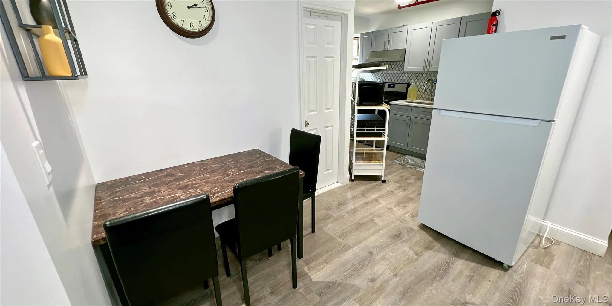 Kitchen with freestanding refrigerator, decorative backsplash, stainless steel range oven, light wood-style floors, and gray cabinets Kitchen with freestanding refrigerator, decorative backsplash, stainless steel range oven, light wood-style floors, and gray cabinets