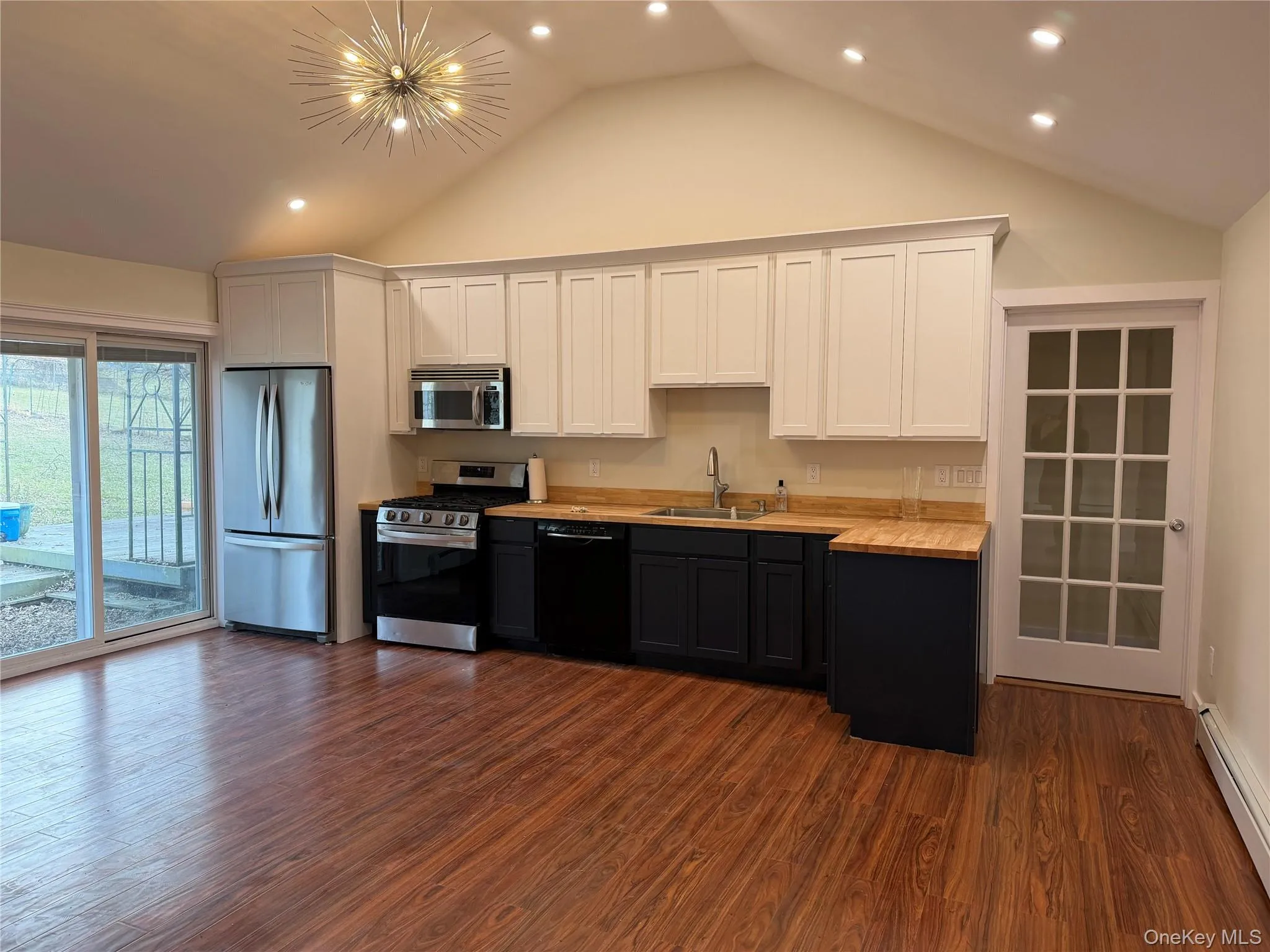 Kitchen with white cabinets, appliances with stainless steel finishes, a baseboard heating unit, dark wood-type flooring, and recessed lighting Kitchen with white cabinets, appliances with stainless steel finishes, a baseboard heating unit, dark wood-type flooring, and recessed lighting