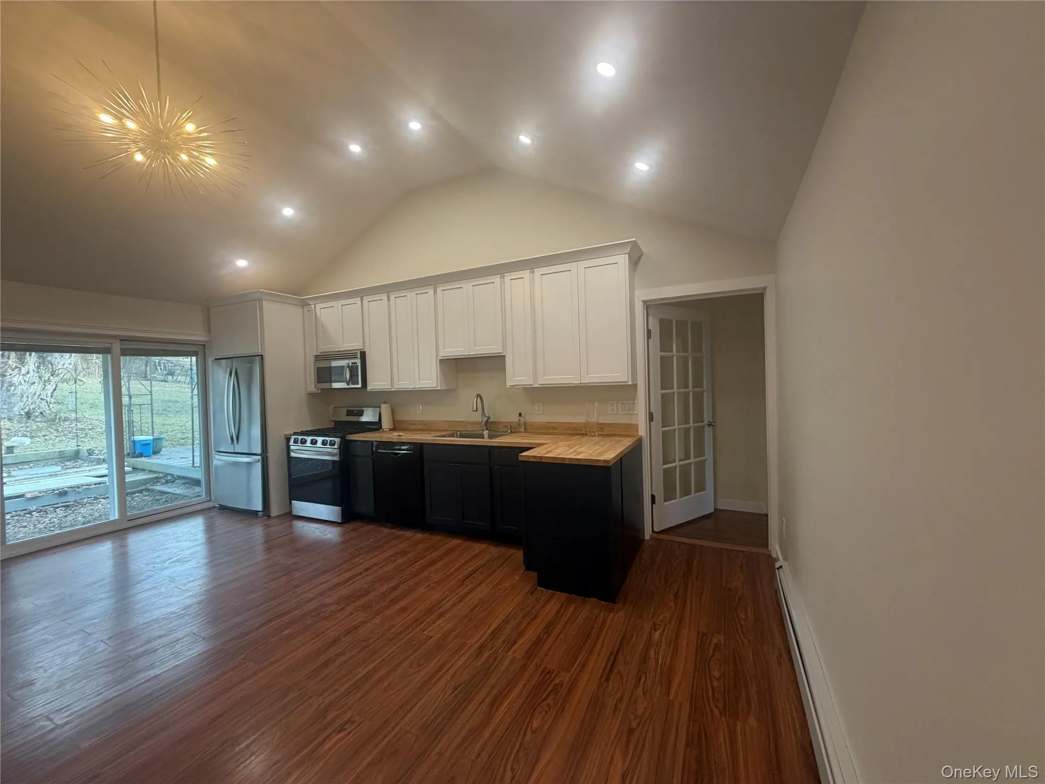 Kitchen with white cabinets, appliances with stainless steel finishes, dark wood-type flooring, a baseboard heating unit, and wooden counters Kitchen with white cabinets, appliances with stainless steel finishes, dark wood-type flooring, a baseboard heating unit, and wooden counters
