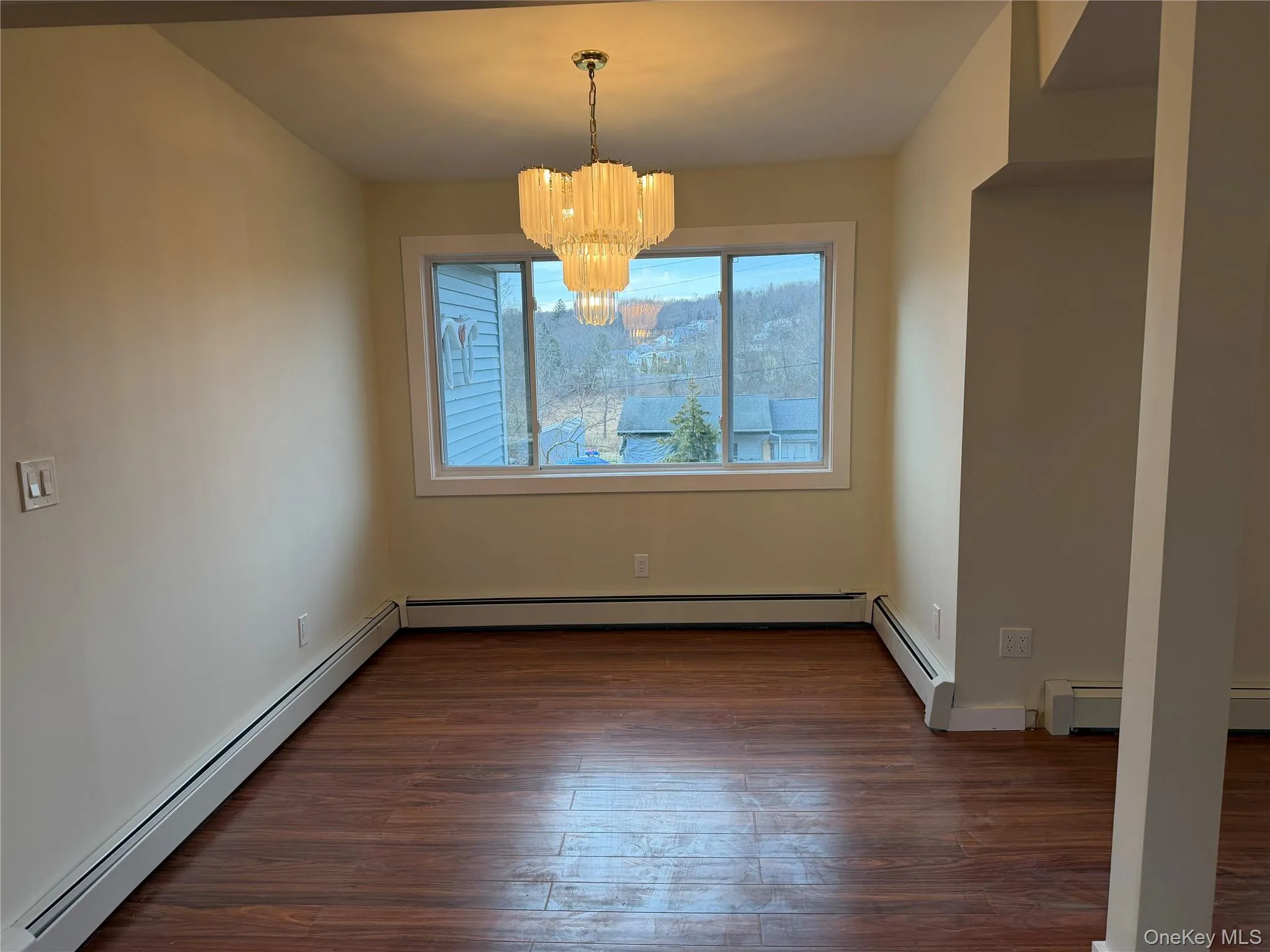 Unfurnished dining area with a baseboard heating unit, dark wood-style flooring, and a chandelier Unfurnished dining area with a baseboard heating unit, dark wood-style flooring, and a chandelier