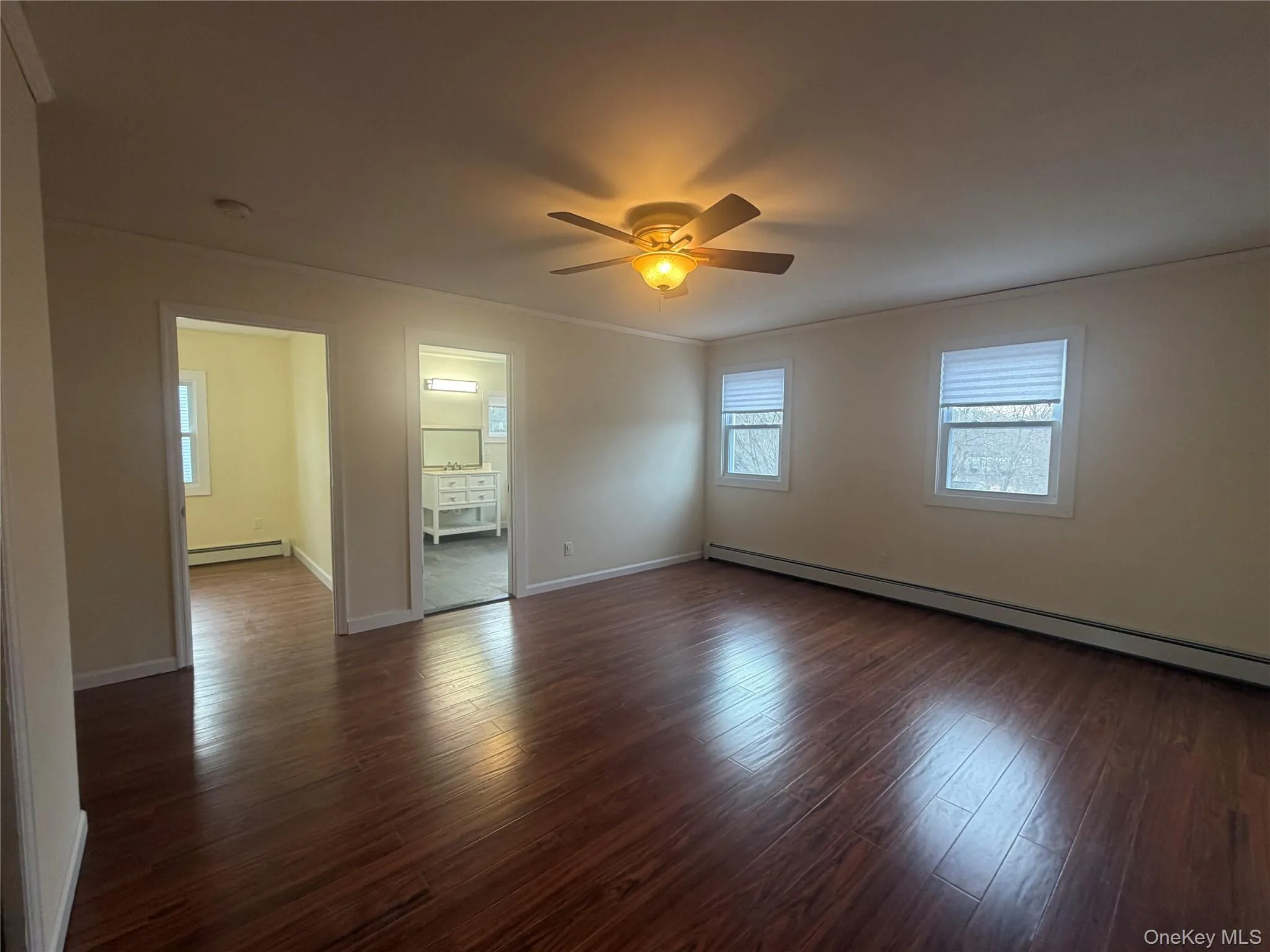 Spare room featuring a baseboard heating unit, dark wood-type flooring, crown molding, and ceiling fan Spare room featuring a baseboard heating unit, dark wood-type flooring, crown molding, and ceiling fan