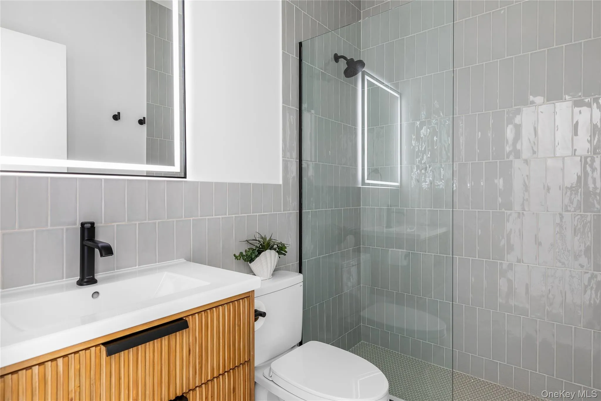 Bathroom featuring tile walls, vanity, a walk in shower, and tasteful backsplash Bathroom featuring tile walls, vanity, a walk in shower, and tasteful backsplash