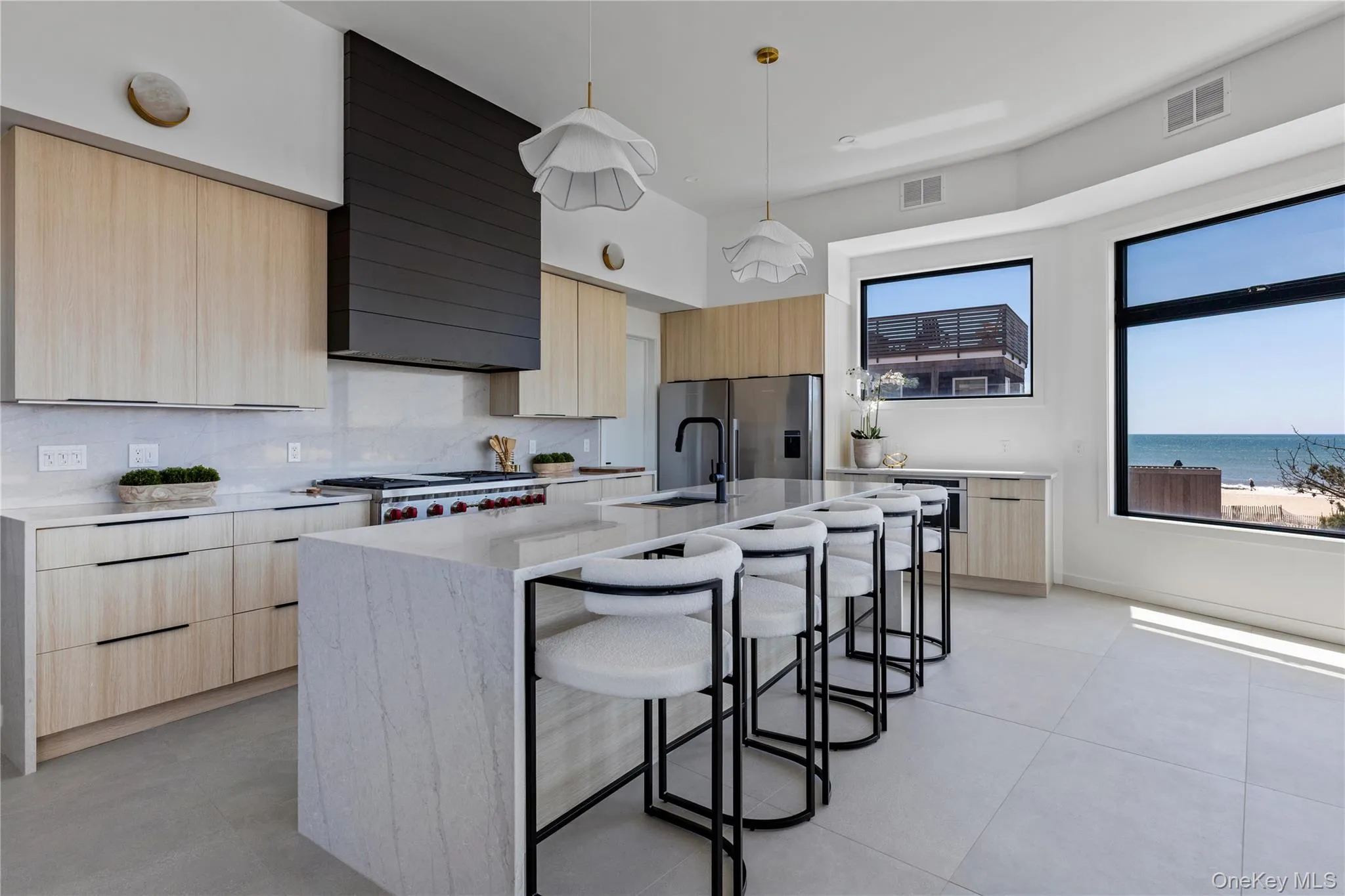 Kitchen with light brown cabinetry, modern cabinets, a breakfast bar, and hanging light fixtures Kitchen with light brown cabinetry, modern cabinets, a breakfast bar, and hanging light fixtures