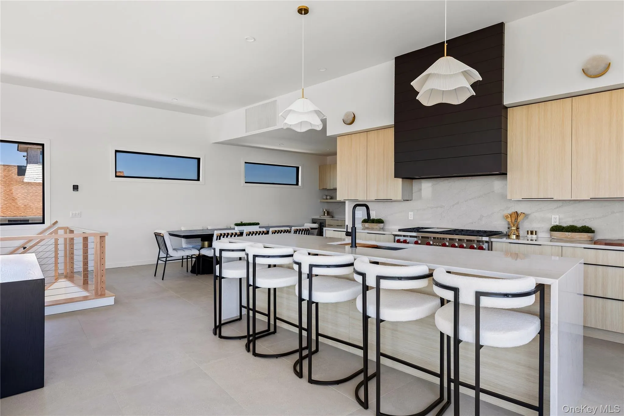 Kitchen featuring light brown cabinetry, modern cabinets, decorative backsplash, a breakfast bar, and hanging light fixtures Kitchen featuring light brown cabinetry, modern cabinets, decorative backsplash, a breakfast bar, and hanging light fixtures