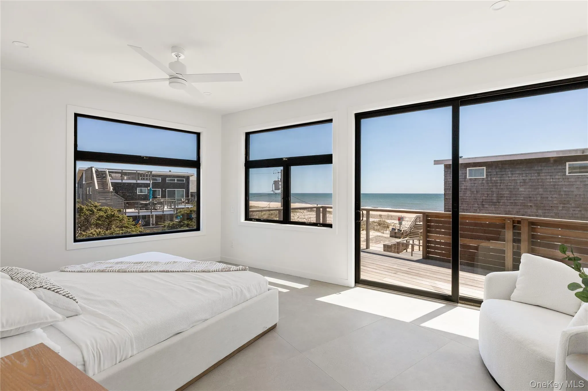 Bedroom featuring view of water and beach, access to exterior, and a ceiling fan Bedroom featuring view of water and beach, access to exterior, and a ceiling fan