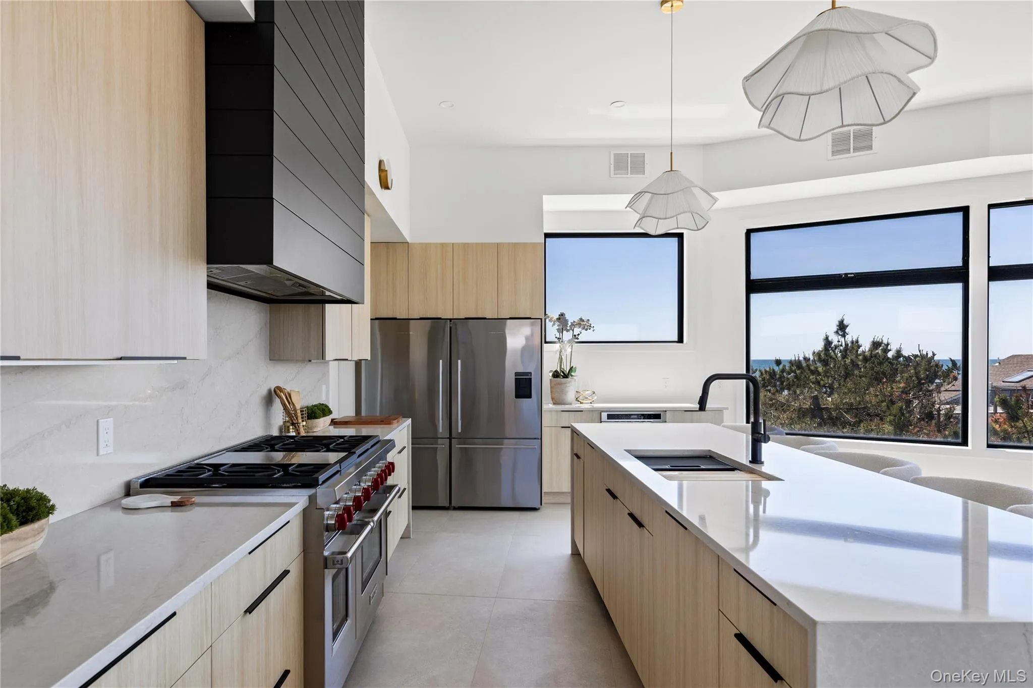 Kitchen with light brown cabinets, stainless steel appliances, light stone countertops, modern cabinets, and decorative backsplash Kitchen with light brown cabinets, stainless steel appliances, light stone countertops, modern cabinets, and decorative backsplash