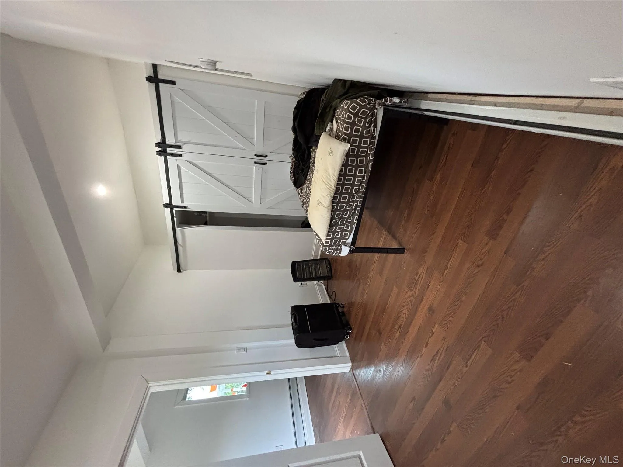 Bedroom featuring dark wood-style flooring, a barn door, a baseboard heating unit, and recessed lighting Bedroom featuring dark wood-style flooring, a barn door, a baseboard heating unit, and recessed lighting