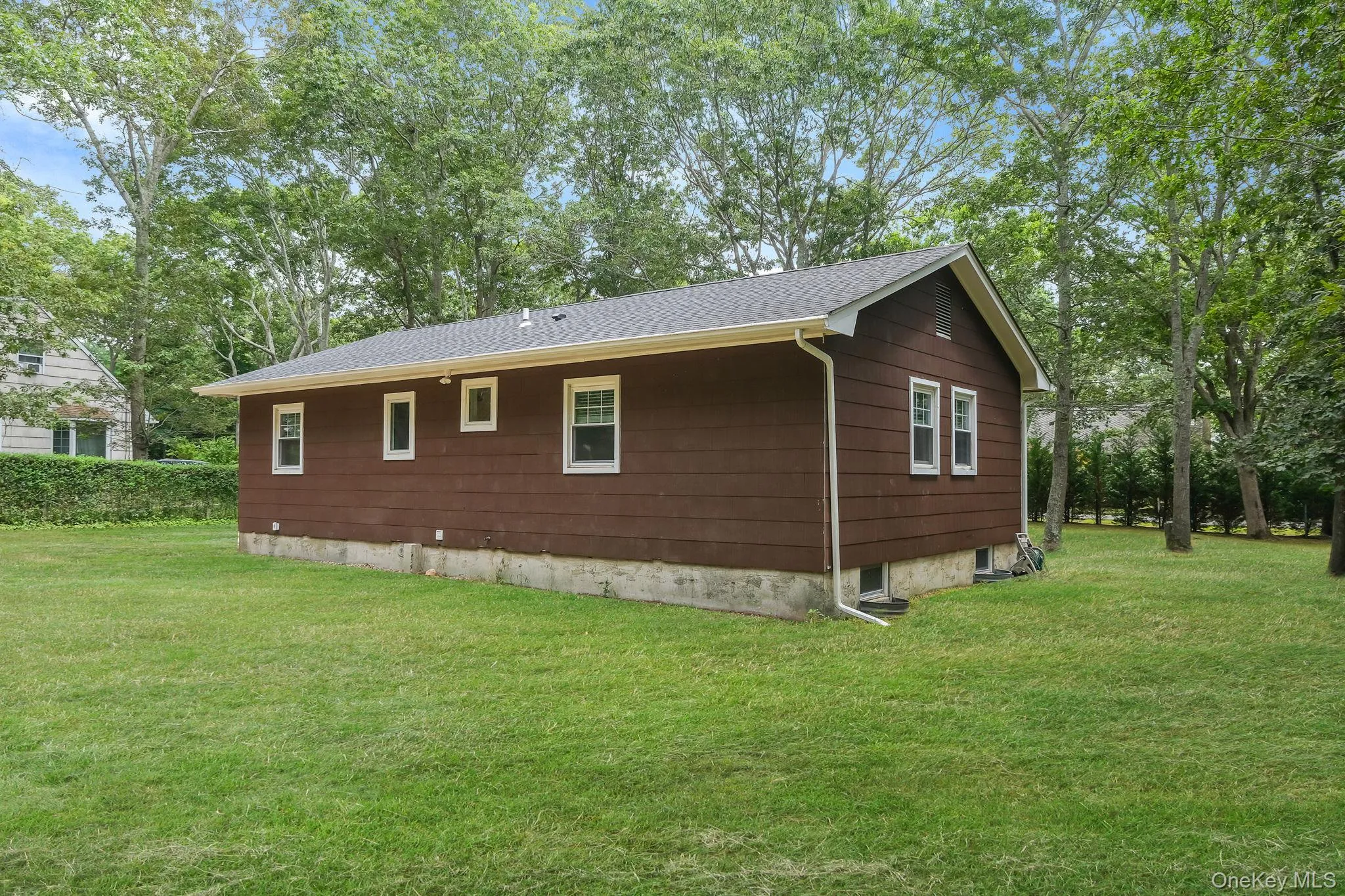 View of home's exterior with a yard, a shingled roof, and view of scattered trees