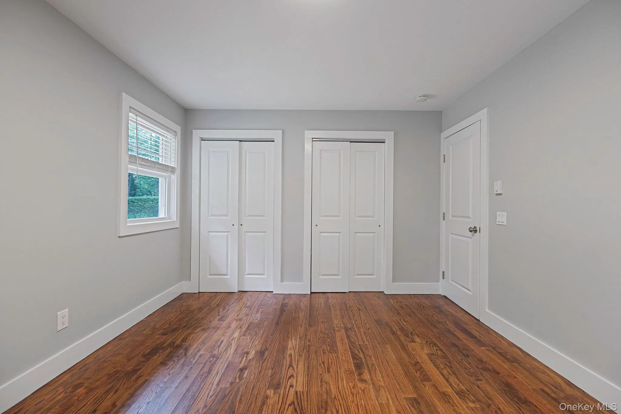 Unfurnished bedroom featuring multiple closets and dark wood finished floors