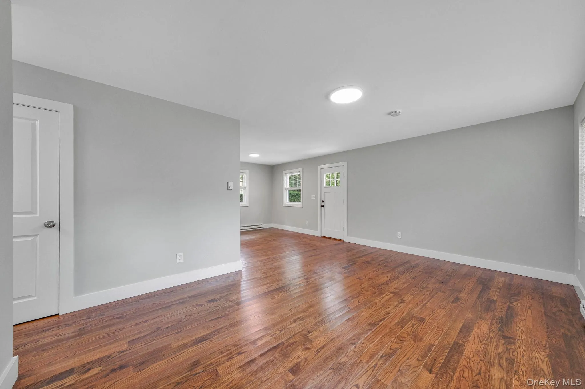 Empty room with dark wood-type flooring and baseboards