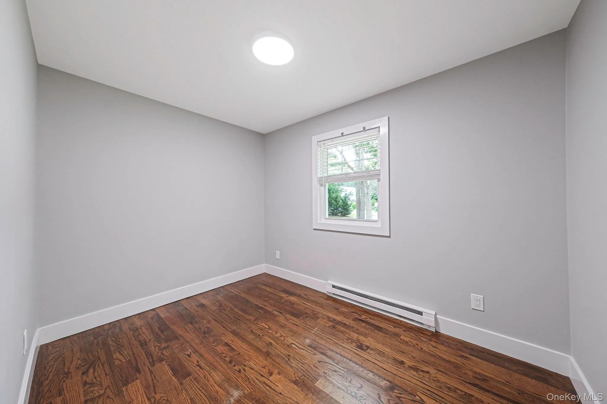 Unfurnished room with a baseboard radiator and dark wood-style floors