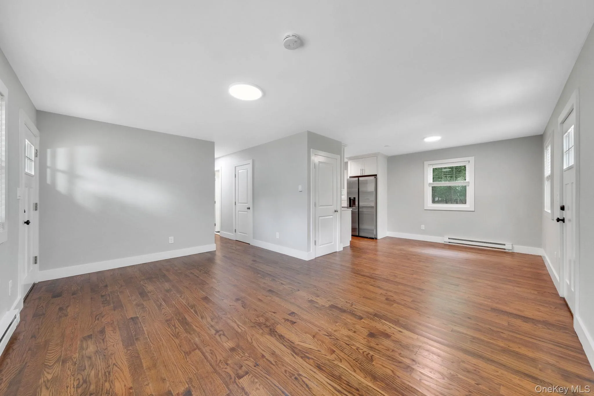 Unfurnished living room featuring dark wood finished floors and a baseboard radiator