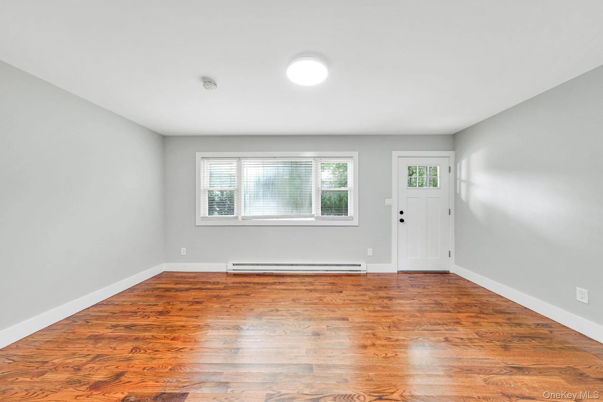 Entrance foyer featuring wood finished floors and a baseboard heating unit