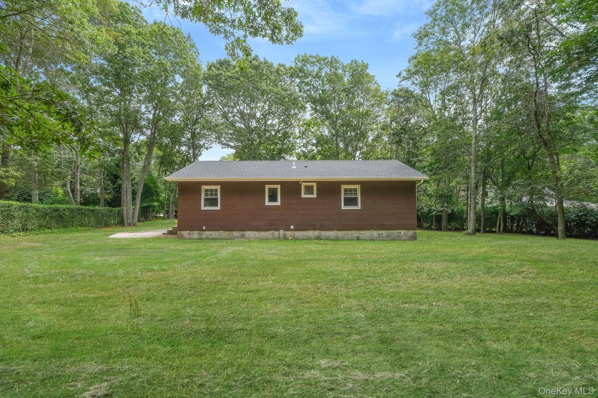 View of side of home featuring a lawn and view of scattered trees