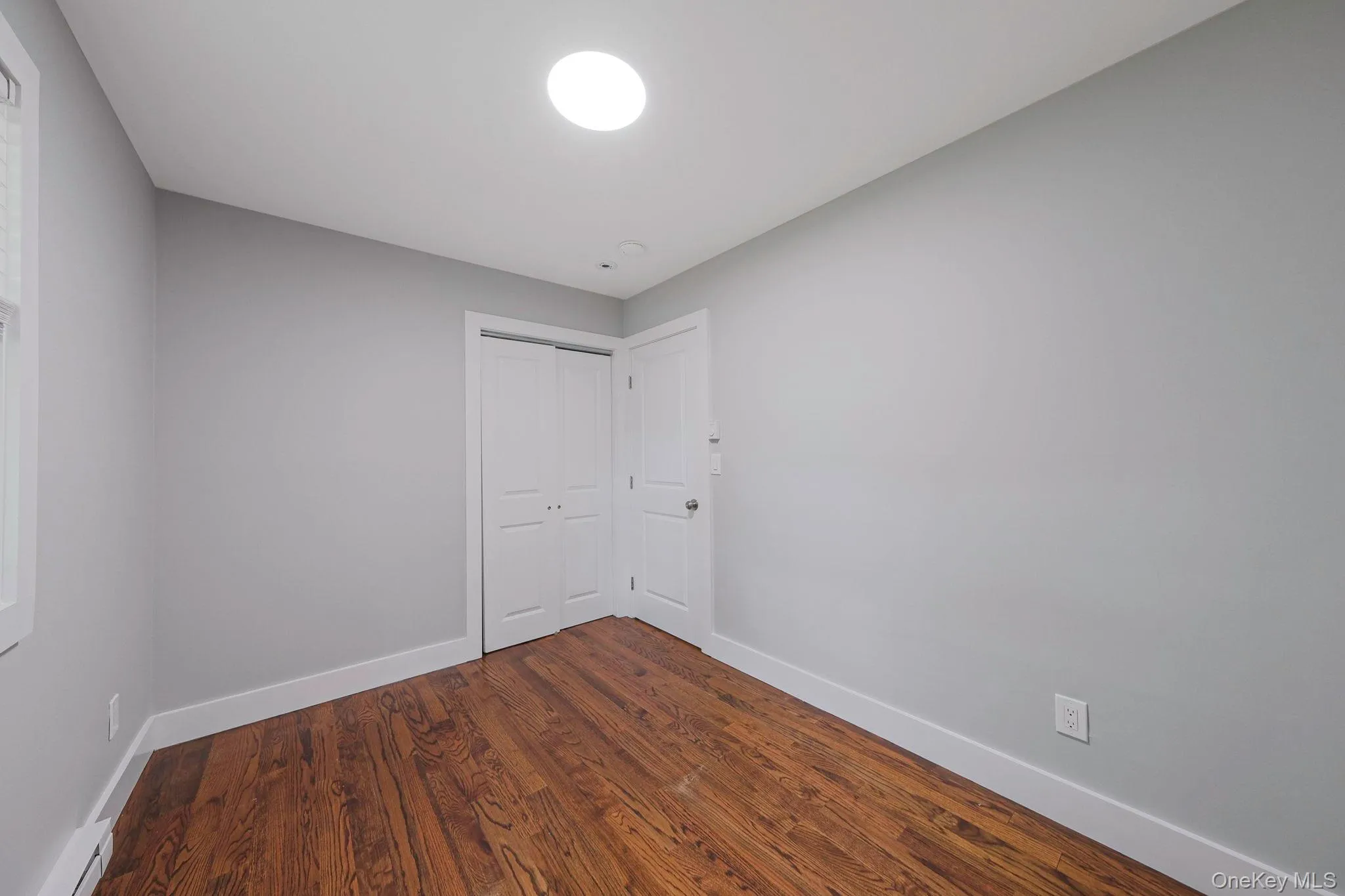 Unfurnished room featuring dark wood finished floors and a baseboard heating unit
