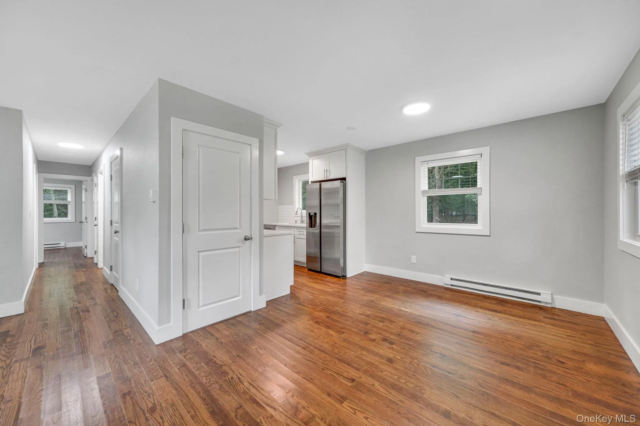 Unfurnished living room with a baseboard heating unit, dark wood-type flooring, and recessed lighting