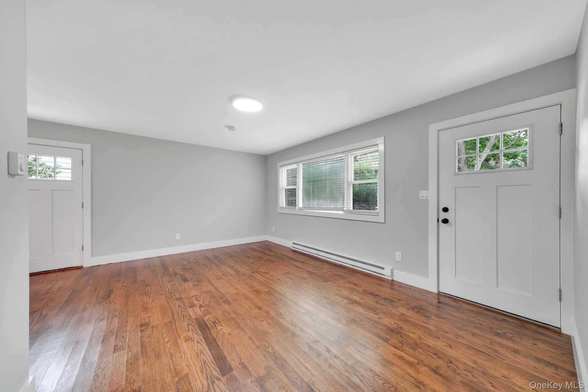 Foyer featuring a baseboard heating unit and wood finished floors