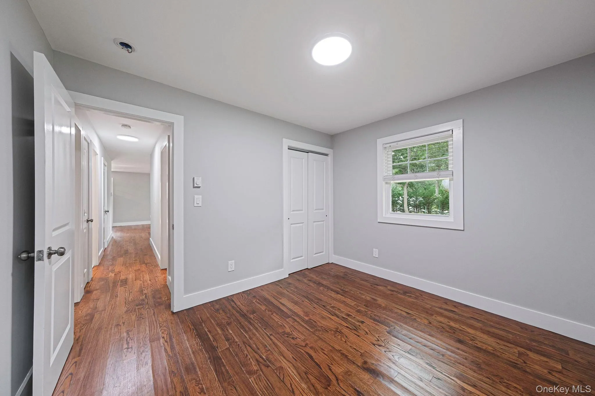 Unfurnished bedroom with dark wood-style flooring and a closet