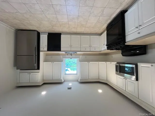 Kitchen with stove, stainless steel fridge, light countertops, and recessed lighting Kitchen with stove, stainless steel fridge, light countertops, and recessed lighting