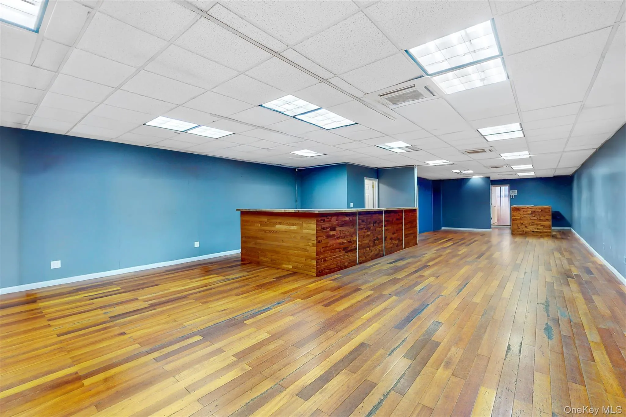 Empty room with light wood-style floors, a community bar, and a drop ceiling Empty room with light wood-style floors, a community bar, and a drop ceiling