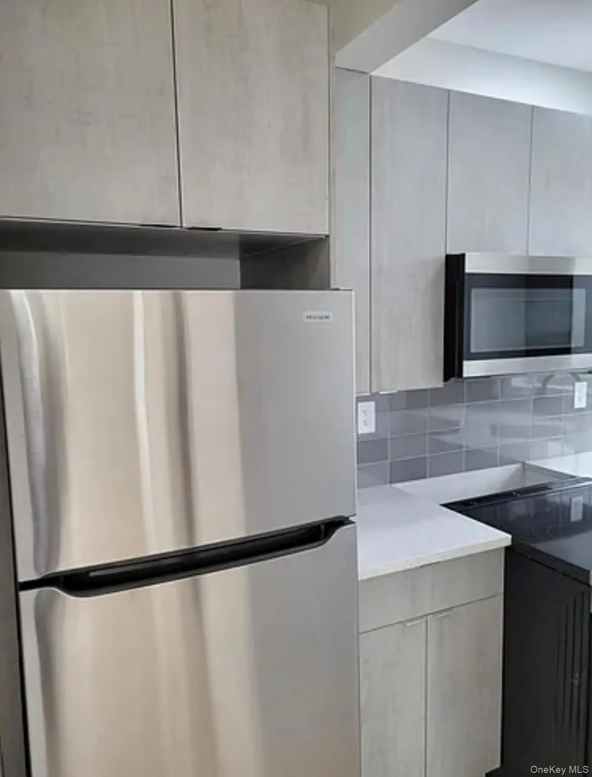 Kitchen featuring appliances with stainless steel finishes, decorative backsplash, modern cabinets, and light stone counters Kitchen featuring appliances with stainless steel finishes, decorative backsplash, modern cabinets, and light stone counters