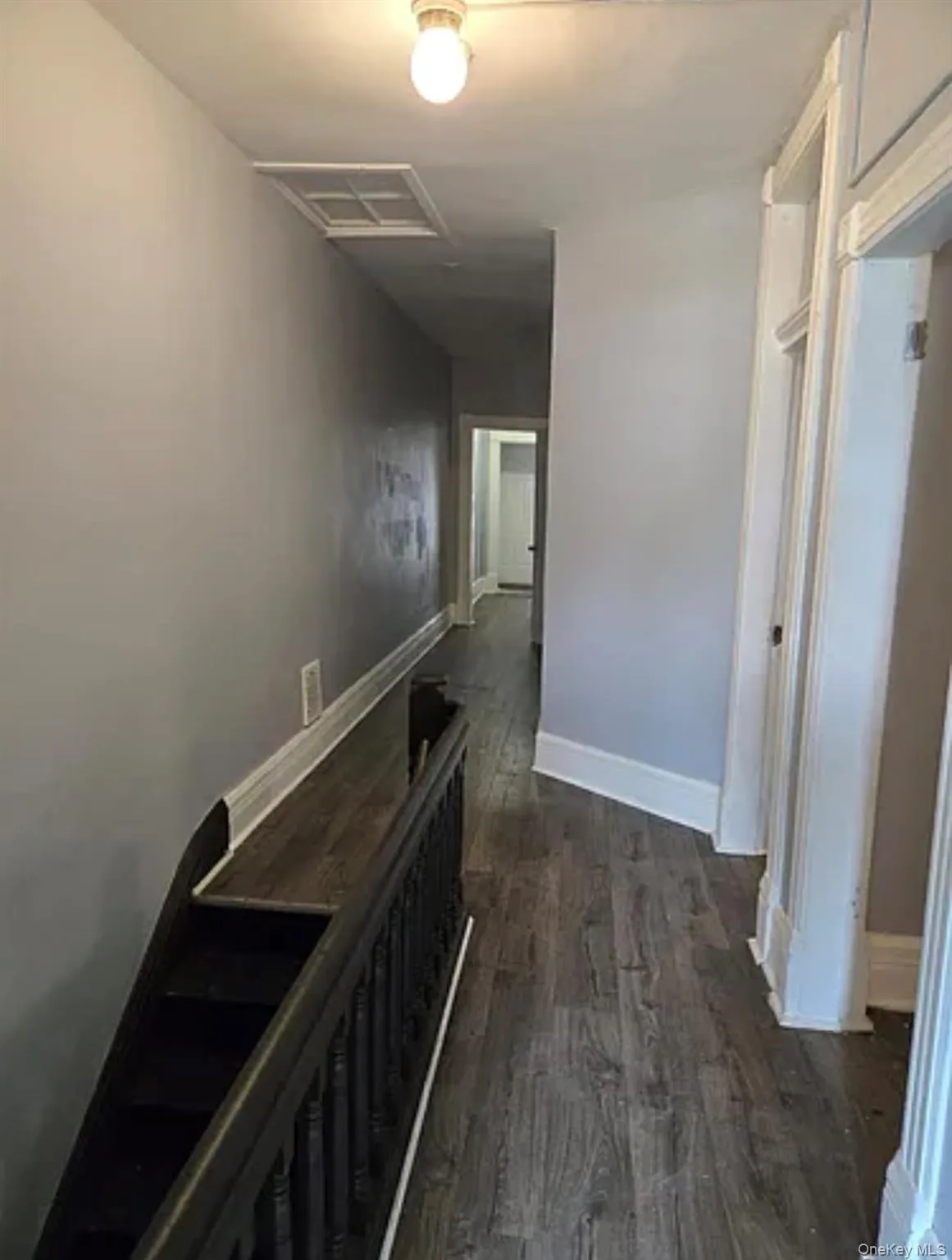 Hallway with dark wood-type flooring and baseboards Hallway with dark wood-type flooring and baseboards
