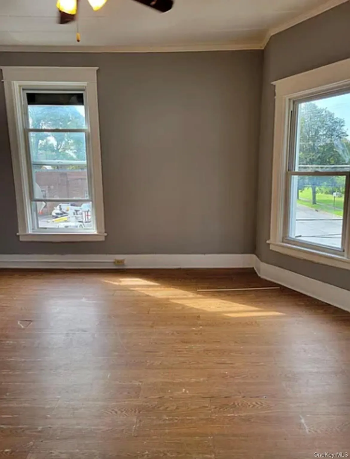 Spare room with wood finished floors, ornamental molding, and a ceiling fan Spare room with wood finished floors, ornamental molding, and a ceiling fan
