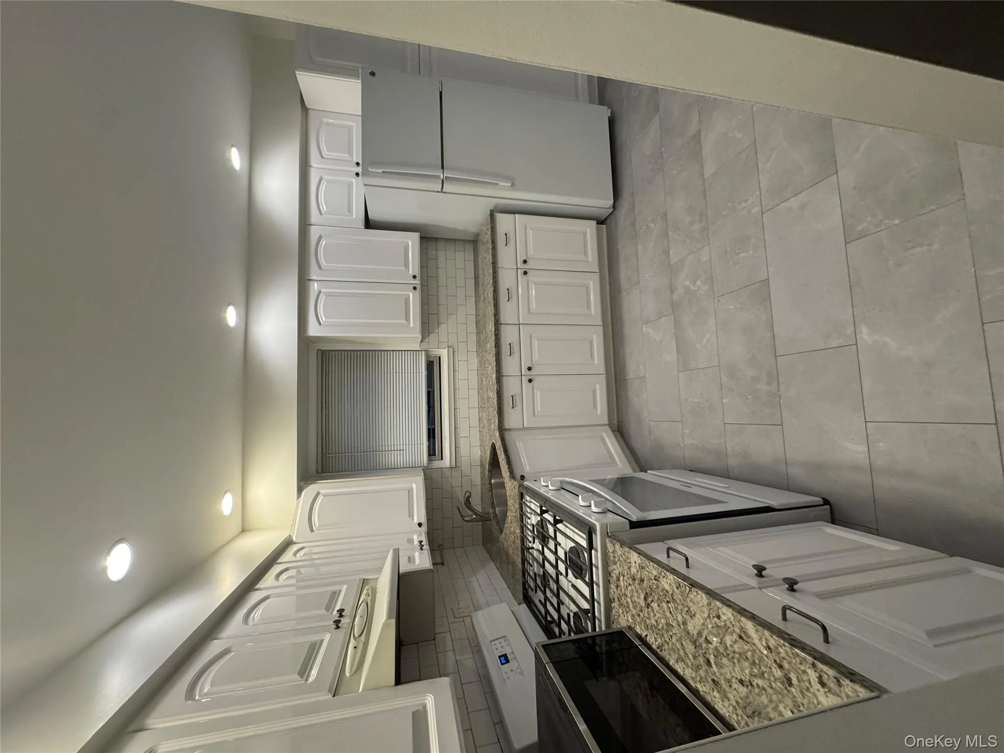 Kitchen with white cabinets, stainless steel stove, fridge, light stone countertops, and backsplash Kitchen with white cabinets, stainless steel stove, fridge, light stone countertops, and backsplash