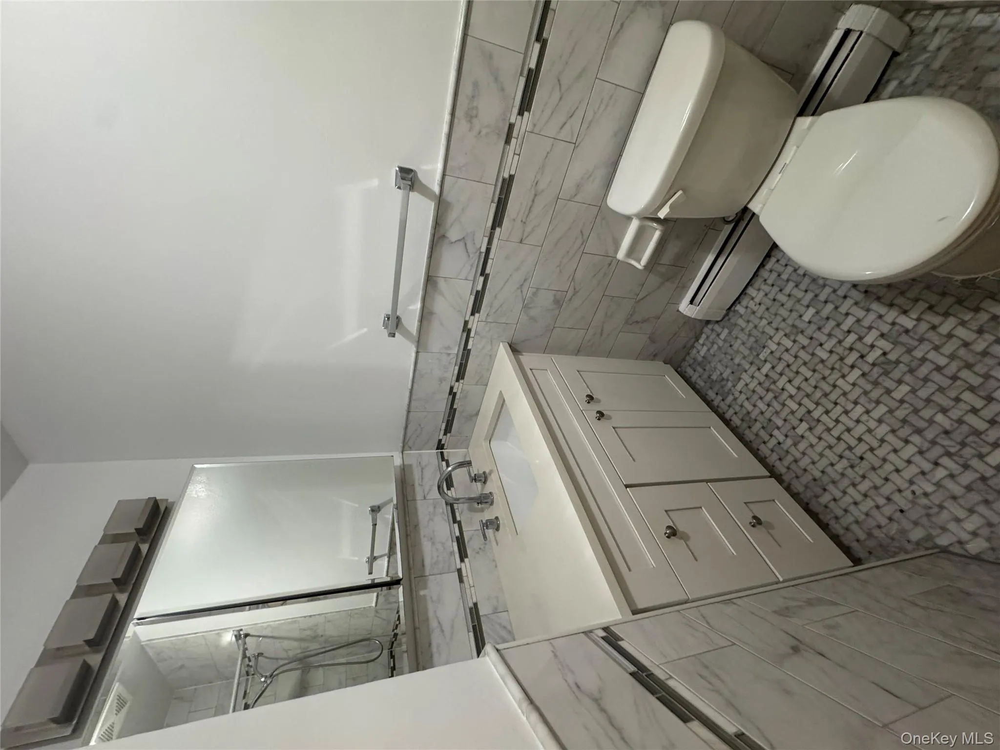 Full bath featuring vanity, a baseboard radiator, tile walls, a wainscoted wall, and a shower Full bath featuring vanity, a baseboard radiator, tile walls, a wainscoted wall, and a shower