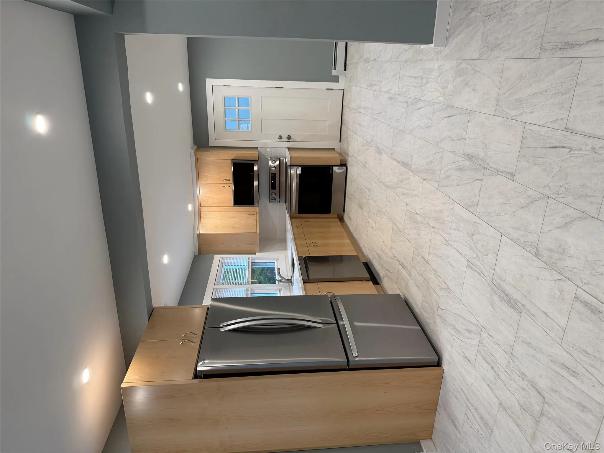 Kitchen featuring stainless steel appliances, light brown cabinetry, recessed lighting, a baseboard radiator, and modern cabinets Kitchen featuring stainless steel appliances, light brown cabinetry, recessed lighting, a baseboard radiator, and modern cabinets