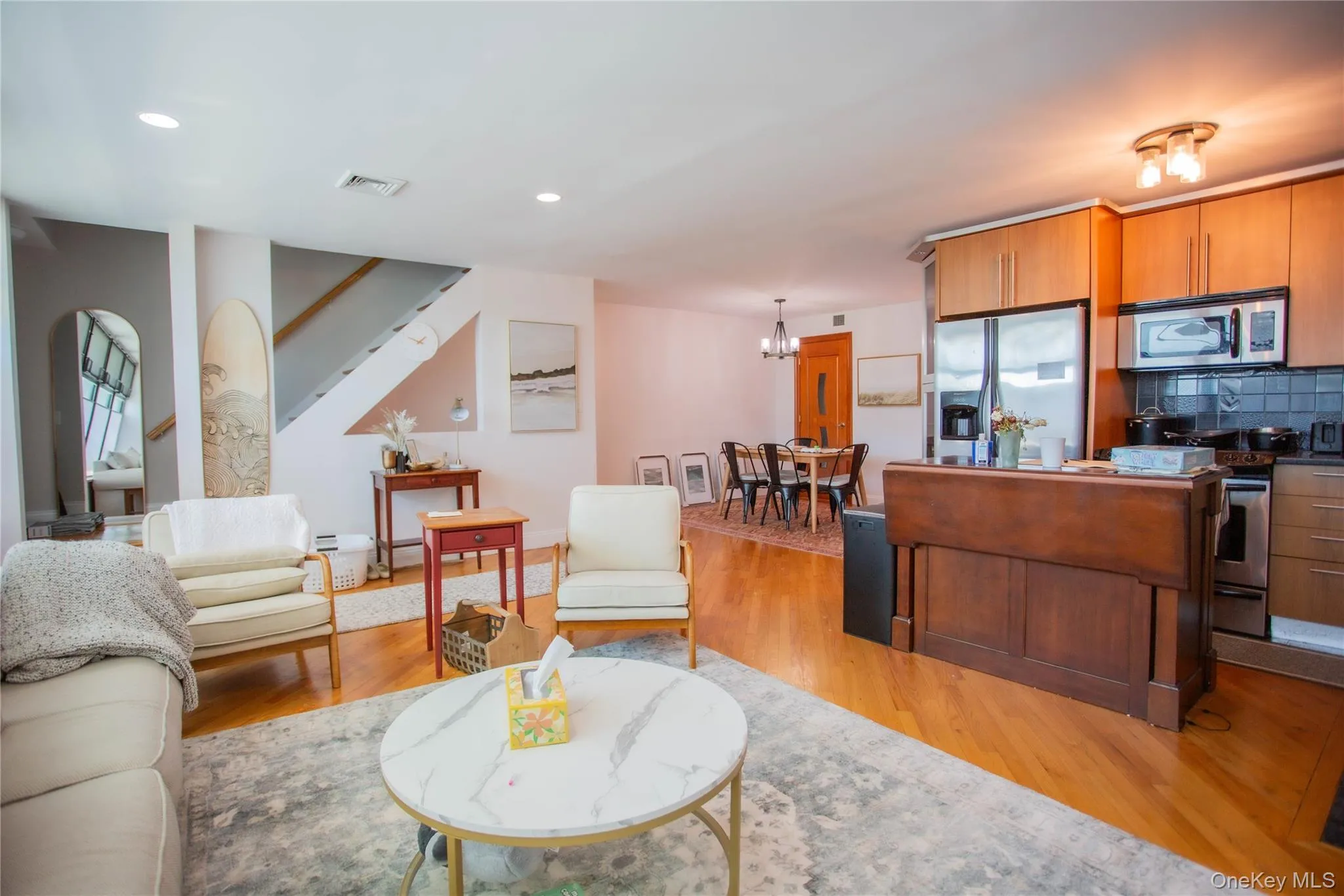 Living area with light wood-type flooring, recessed lighting, a chandelier, and stairway Living area with light wood-type flooring, recessed lighting, a chandelier, and stairway