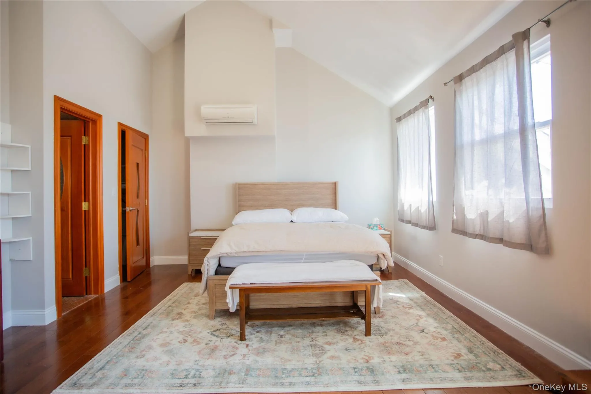 Bedroom with wood finished floors, high vaulted ceiling, and a wall mounted AC Bedroom with wood finished floors, high vaulted ceiling, and a wall mounted AC