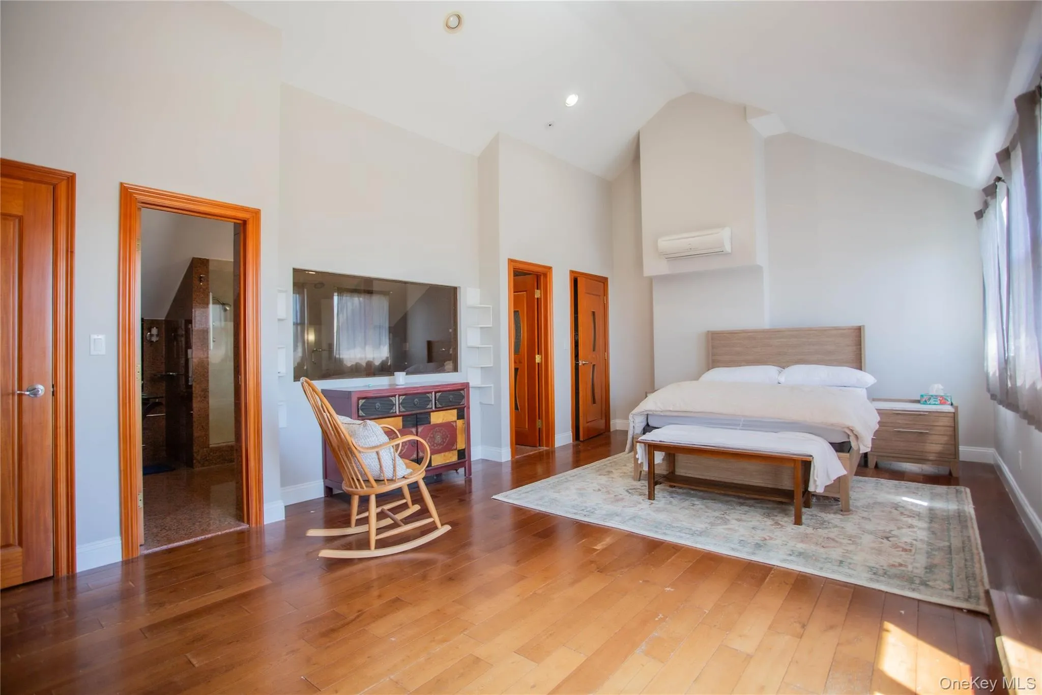 Bedroom with high vaulted ceiling, wood-type flooring, a wall mounted AC, and recessed lighting Bedroom with high vaulted ceiling, wood-type flooring, a wall mounted AC, and recessed lighting