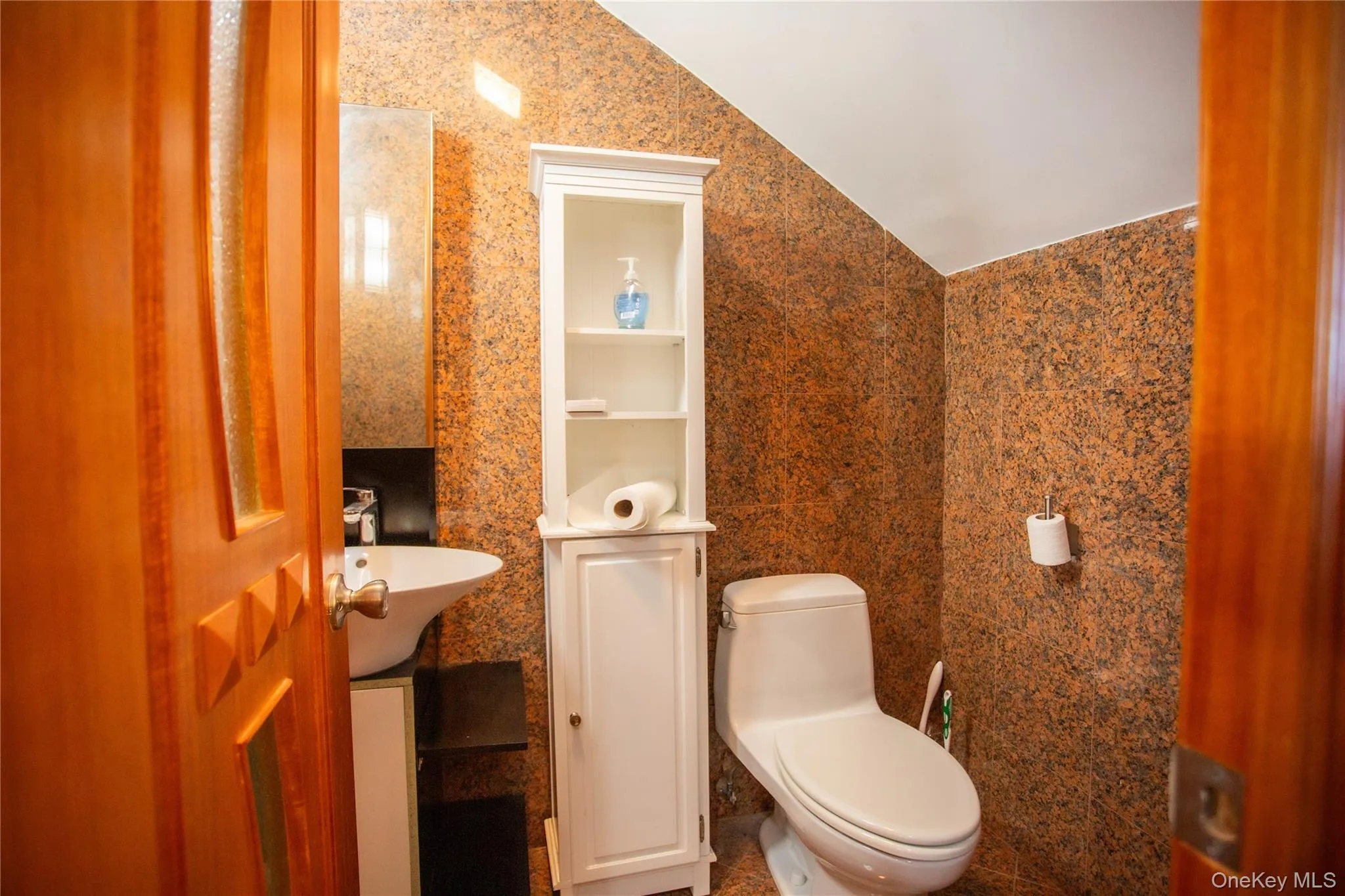 Bathroom featuring tile walls, vanity, and vaulted ceiling Bathroom featuring tile walls, vanity, and vaulted ceiling