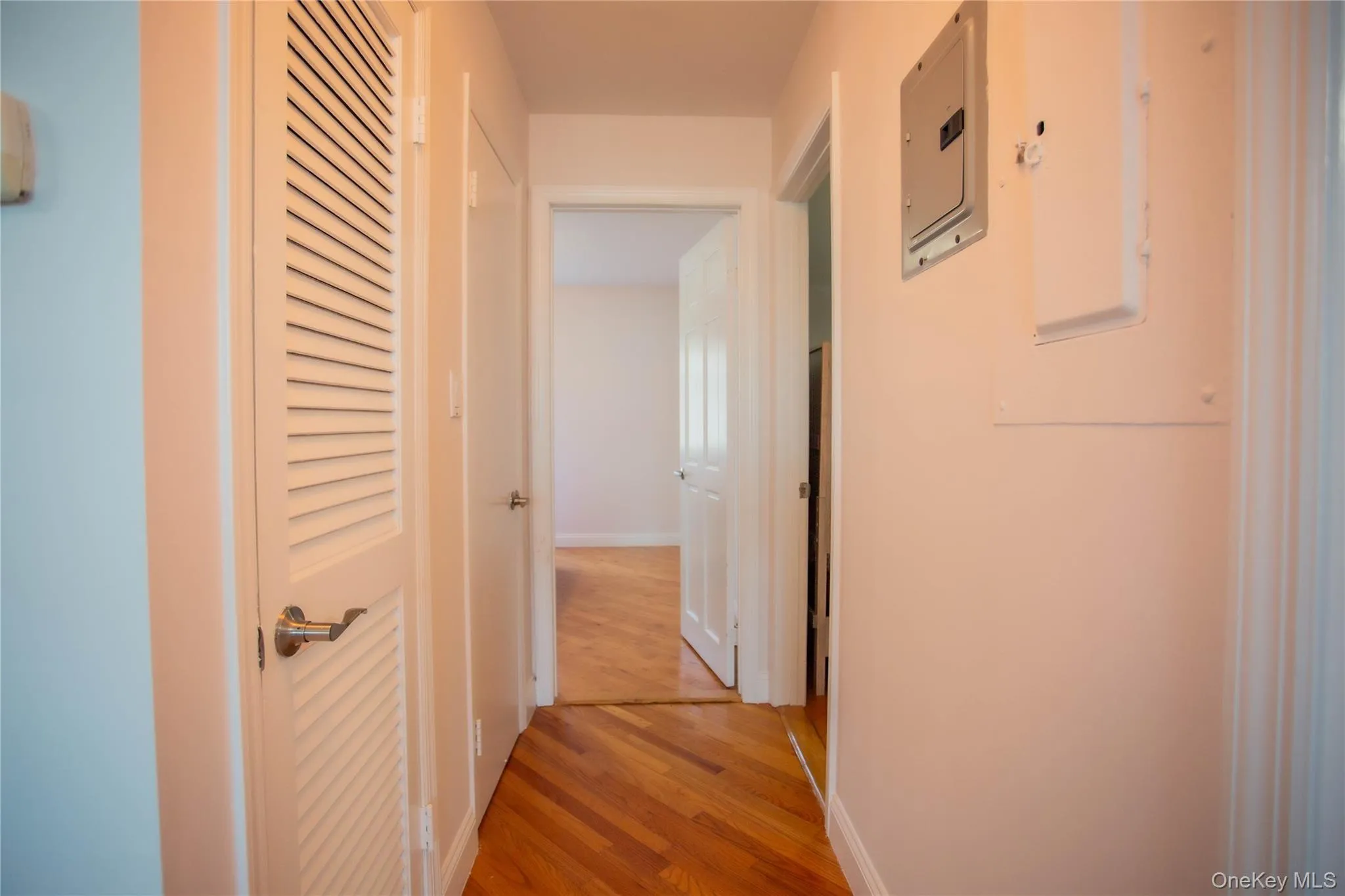 Corridor featuring light wood-type flooring and electric panel Corridor featuring light wood-type flooring and electric panel