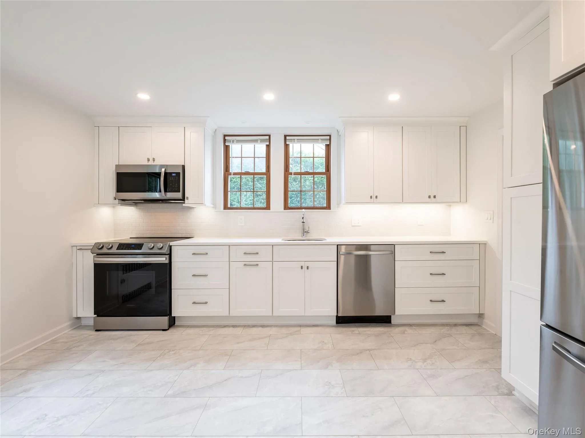 Kitchen with stainless steel appliances, backsplash, white cabinets, and recessed lighting Kitchen with stainless steel appliances, backsplash, white cabinets, and recessed lighting