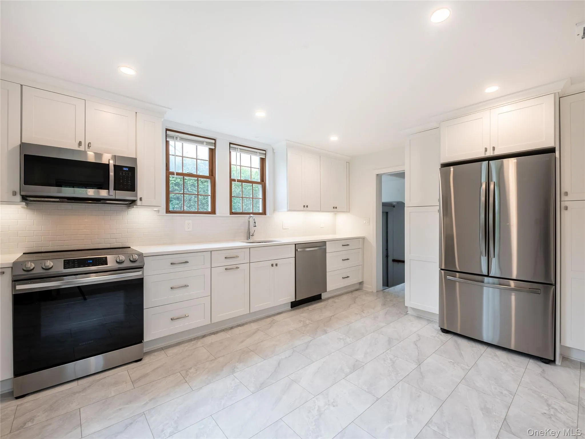 Kitchen with stainless steel appliances, backsplash, white cabinetry, light countertops, and recessed lighting Kitchen with stainless steel appliances, backsplash, white cabinetry, light countertops, and recessed lighting