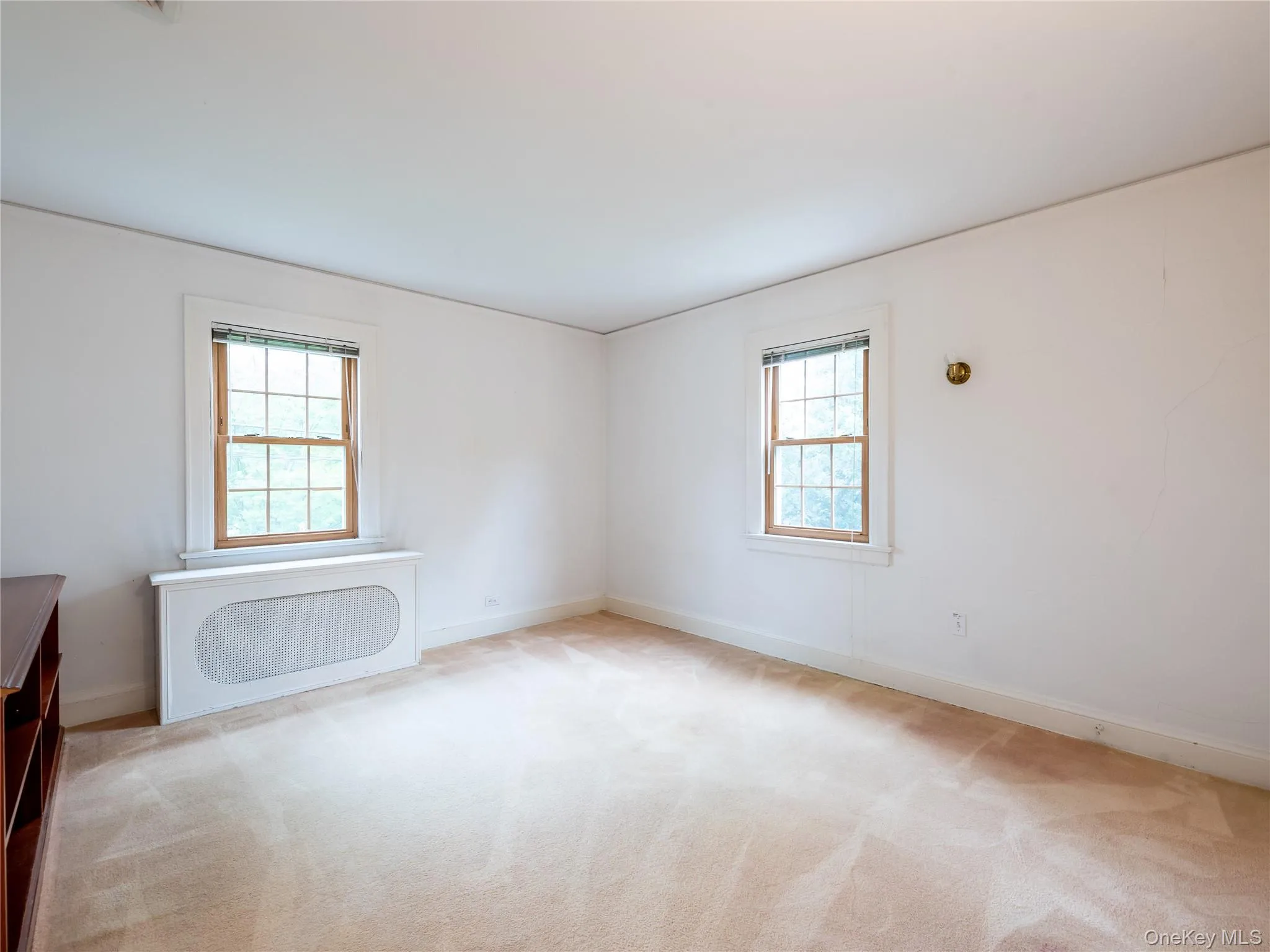 Empty room featuring light colored carpet and radiator heating unit Empty room featuring light colored carpet and radiator heating unit