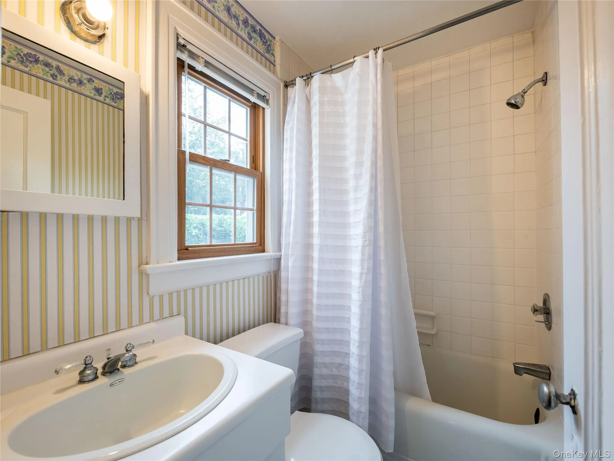 Bathroom featuring wallpapered walls, shower / bath combo, and vanity Bathroom featuring wallpapered walls, shower / bath combo, and vanity