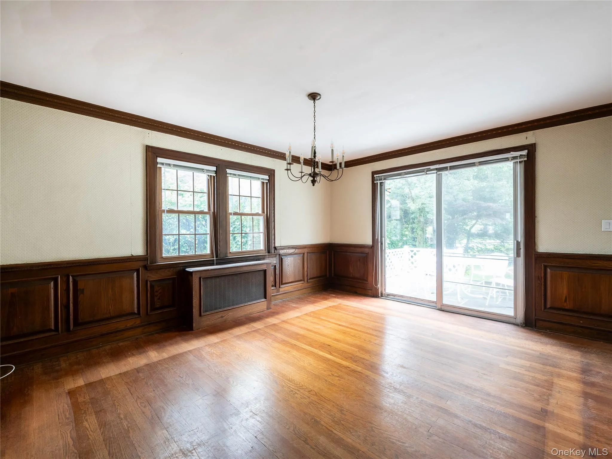 Unfurnished dining area featuring a wainscoted wall, plenty of natural light, a chandelier, light wood-style flooring, and a decorative wall Unfurnished dining area featuring a wainscoted wall, plenty of natural light, a chandelier, light wood-style flooring, and a decorative wall