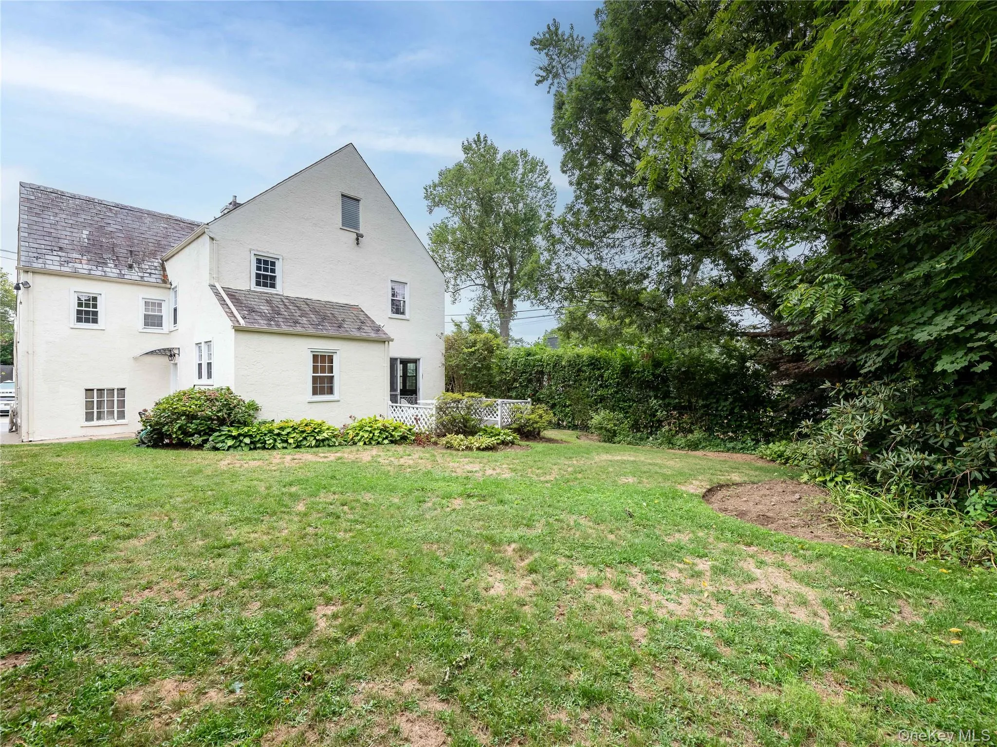 Back of house featuring a high end roof and a lawn Back of house featuring a high end roof and a lawn