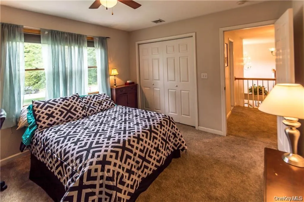 Bedroom featuring dark colored carpet, a closet, and a ceiling fan Bedroom featuring dark colored carpet, a closet, and a ceiling fan
