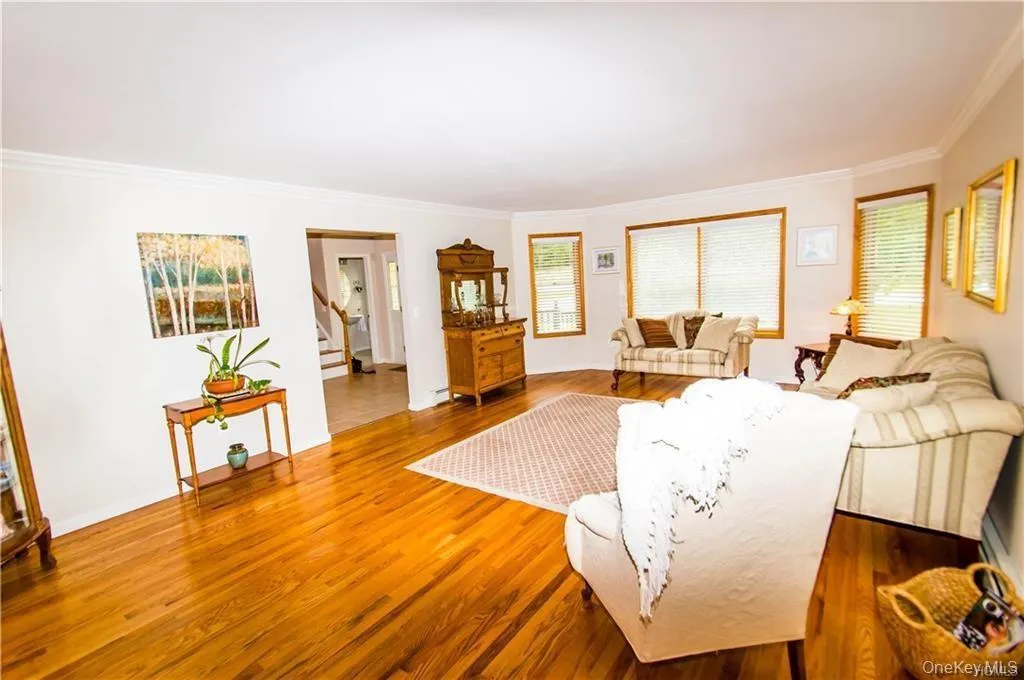 Living room with ornamental molding, stairway, and wood finished floors Living room with ornamental molding, stairway, and wood finished floors
