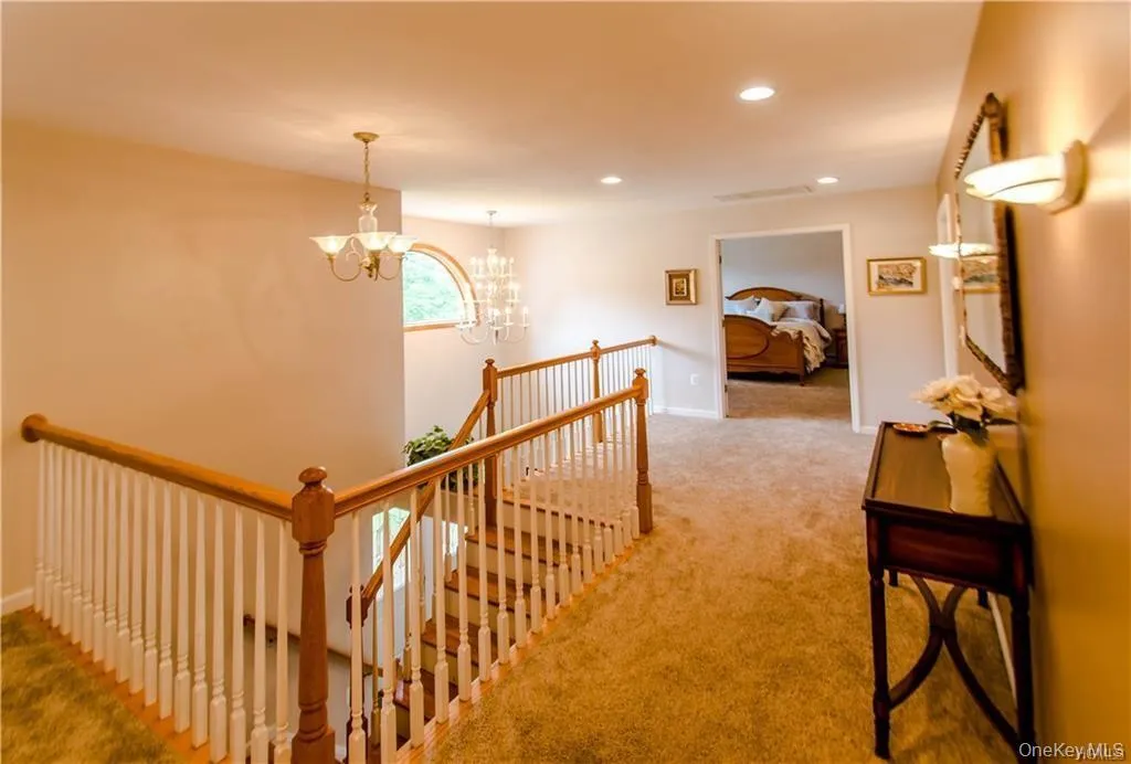 Hall featuring an upstairs landing, recessed lighting, light carpet, and a chandelier Hall featuring an upstairs landing, recessed lighting, light carpet, and a chandelier
