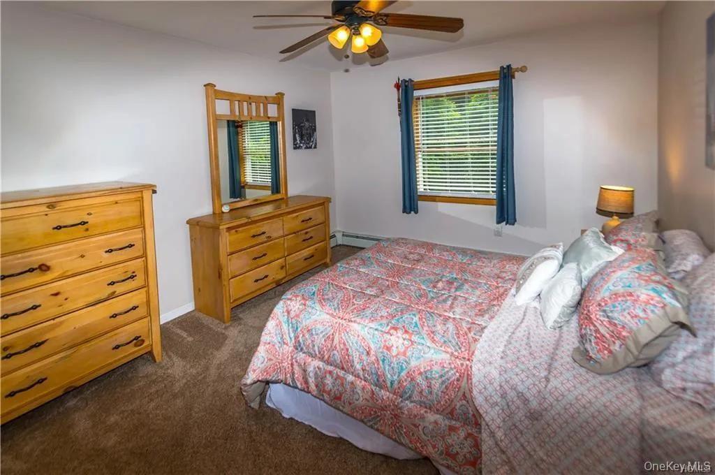 Bedroom with dark colored carpet, a ceiling fan, and a baseboard heating unit Bedroom with dark colored carpet, a ceiling fan, and a baseboard heating unit