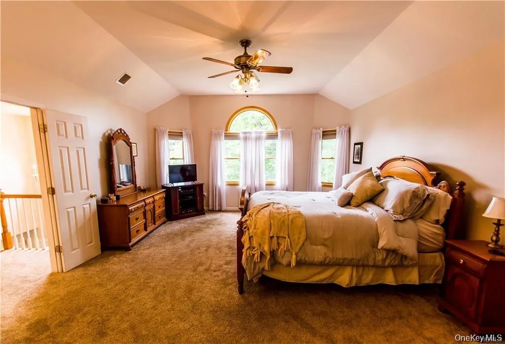 Bedroom featuring vaulted ceiling, carpet, and a ceiling fan Bedroom featuring vaulted ceiling, carpet, and a ceiling fan